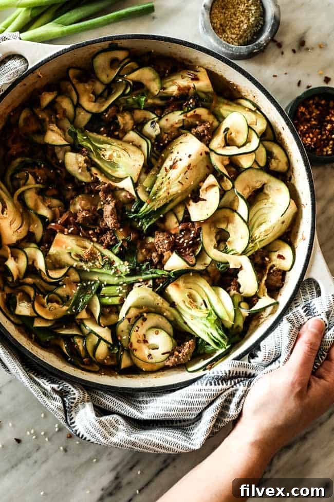 Overhead shot of Szechuan noodles with ground beef and bok choy in a large skillet, ready to serve.