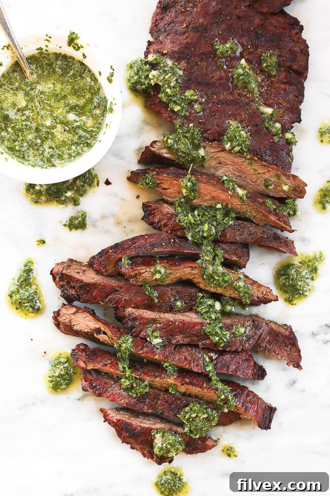 Skirt steak sliced on a marble board with fresh chimichurri sauce drizzled on top