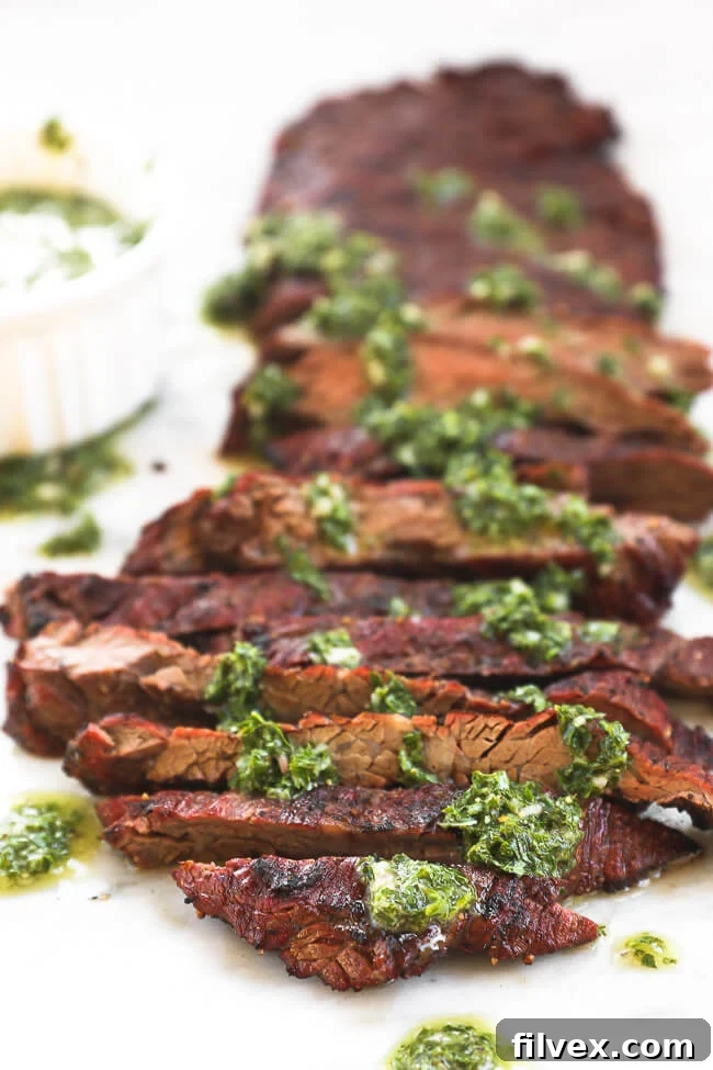 Close up image of sliced steak with chimichurri sauce drizzled all over