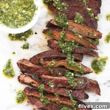 Skirt steak sliced on a marble board with fresh chimichurri sauce drizzled on top