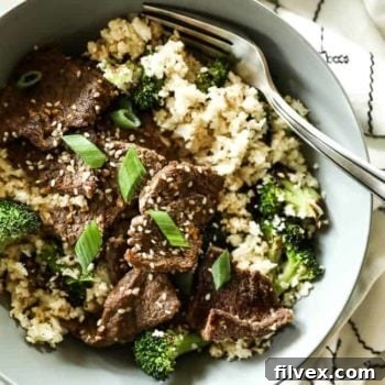 A bowl of Sheet Pan Sesame Beef with cauliflower rice and broccoli.