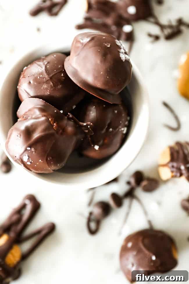 A small bowl filled with chocolate-coated peanut butter balls, generously sprinkled with flaky sea salt, creating an irresistible texture and flavor contrast. These Keto and Paleo friendly treats are a perfect blend of sweet and savory.