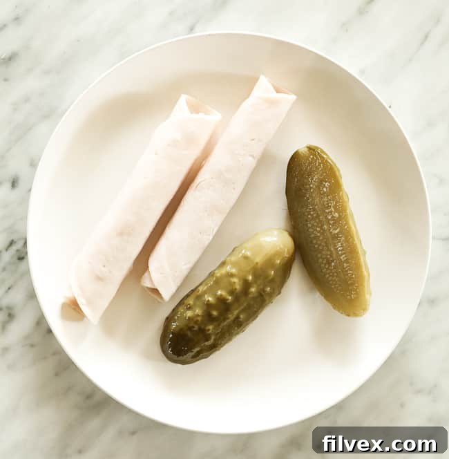Pickles and rolled lunch meat on a plate