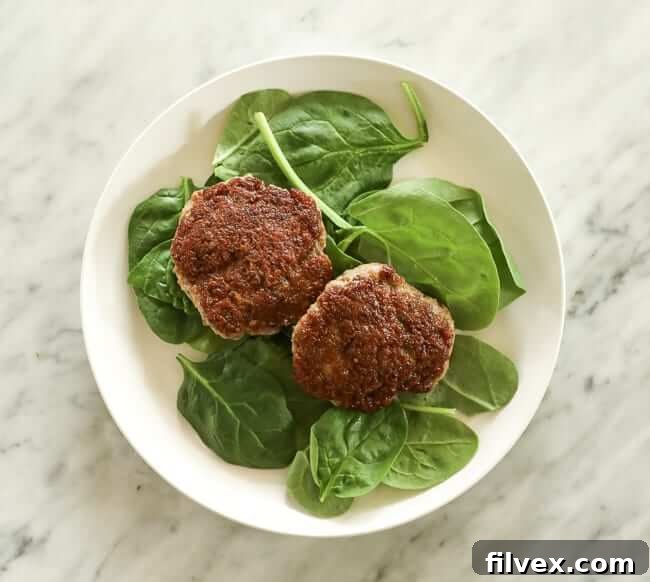 Spinach topped with two sausage patties on a plate