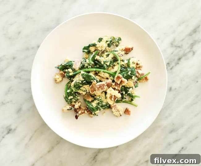 Eggs scrambled with bacon and spinach on a plate