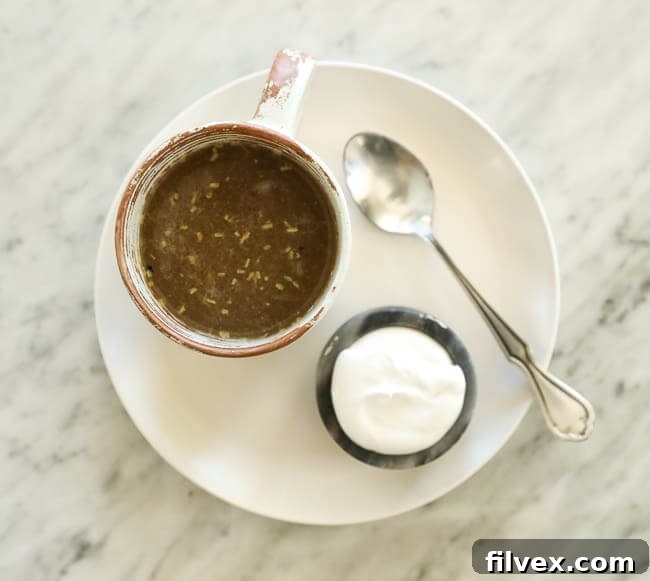 Coconut yogurt and spoon on a plate with a cup of broth