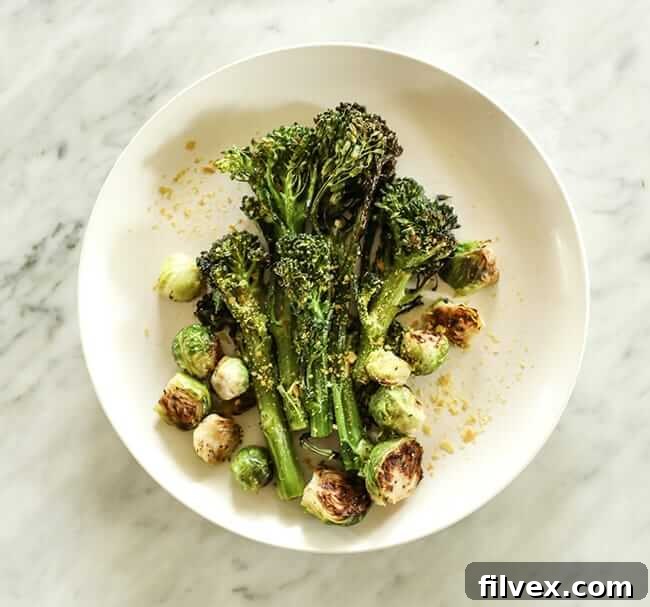 Roasted broccolini and brussels sprouts with nutritional yeast topping on a plate