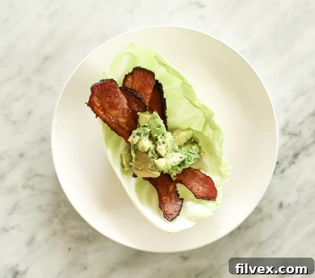 Cabbage leaf topped with bacon and guacamole on a plate