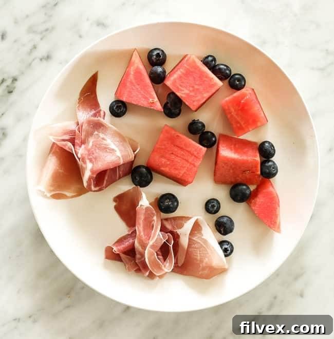 Prosciutto, blueberries and chunks of watermelon on a plate