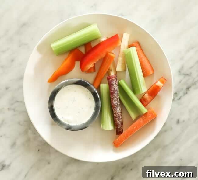 Sliced carrots, celery and bell pepper on a plate with ranch dressing