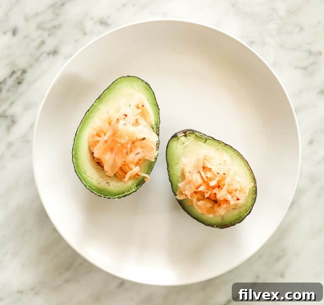 Avocado cut in half and stuffed with kimchi on a plate