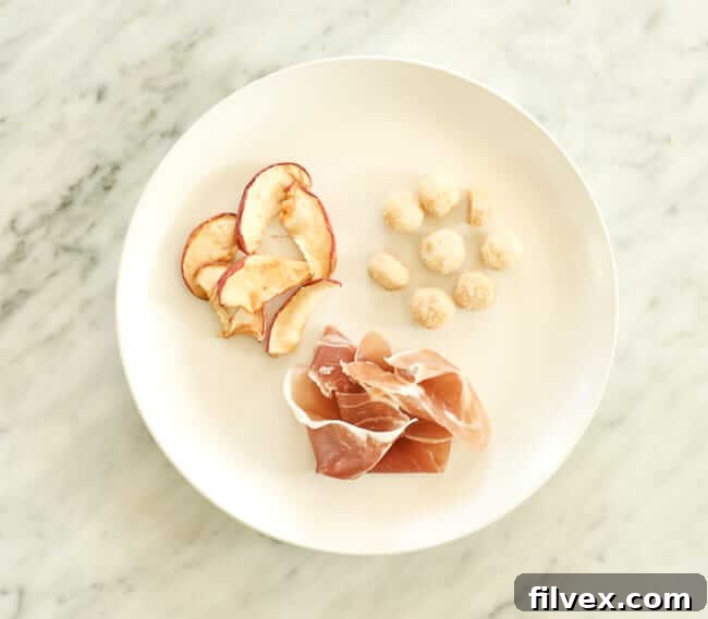 Dried apples, macadamia nuts and prosciutto on a plate