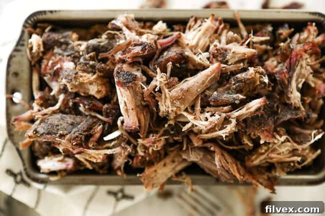 Horizontal image of smoked pork shoulder shredded in a pan, ready to serve or be mixed with sauce.