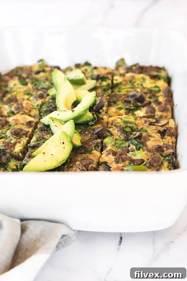 Keto breakfast casserole sliced in a dish with sliced avocado close up angle image