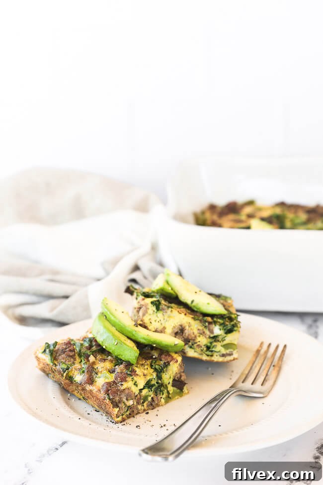 Two pieces of keto breakfast casserole on a plate topped with avocado slices