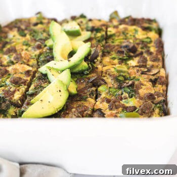 Keto breakfast casserole sliced in a dish with sliced avocado close up angle image