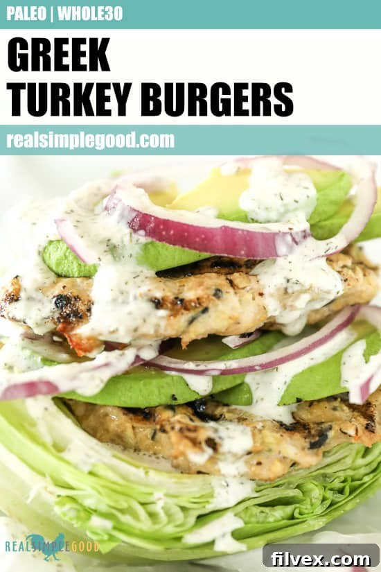 Close-up image of a Greek turkey burger on a lettuce bun with tzatziki sauce dripping down the sides, adorned with avocado and red onion slices. The image is optimized for Pinterest with an inviting visual.