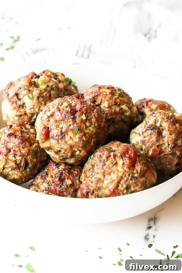 Angled image of a breakfast sausage meatballs piled up in a bowl. Fresh parsley sprinkled on top, showcasing the delicious texture.