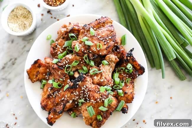 Korean BBQ chicken on a plate with green onions to the right horizontal image