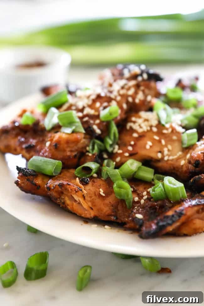 Angle shot of korean bbq chicken stacked on a plate with green onion slices on top