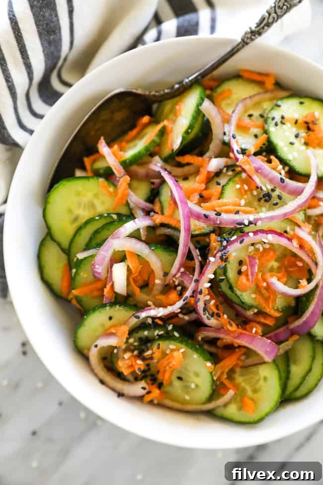 Asian cucumber salad in bowl with spoon vertical image