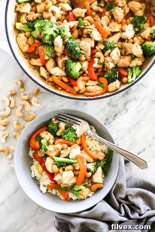 Overhead image of cashew chicken in a skillet and in a bowl served over cauliflower rice with a fork. Chicken, cashews, broccoli, red bell pepper and an asian sauce.