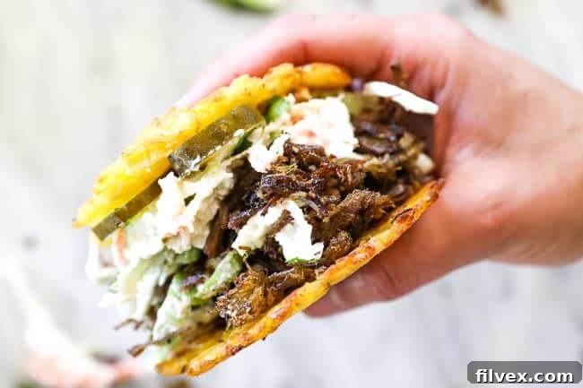 Close up image of holding jibarito - plantain slider with pulled pork, slaw and pickles.