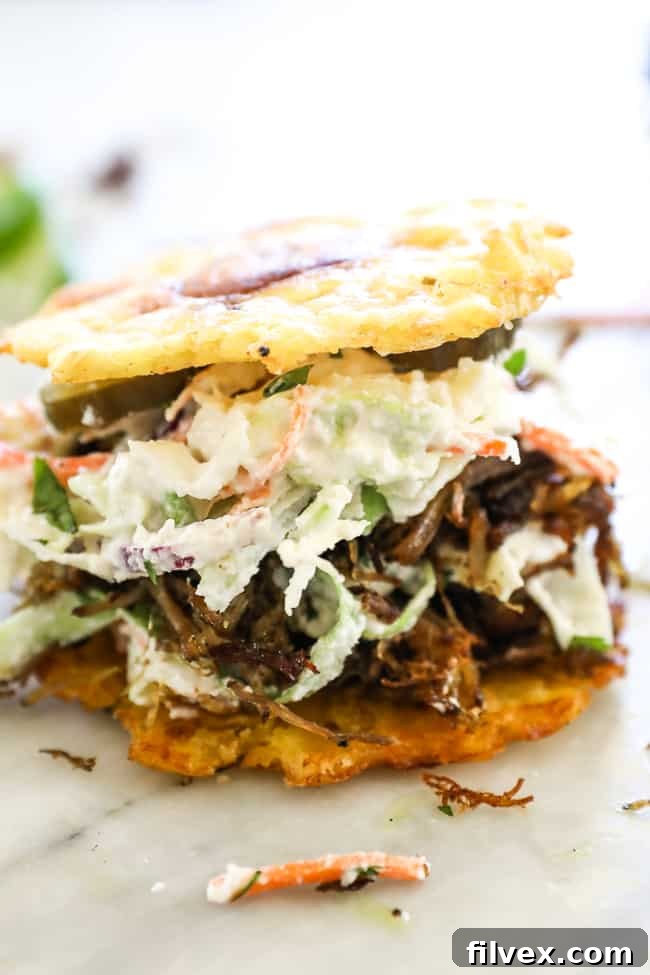 Straight on shot of jibarito with plantain buns, pulled pork, slaw and pickles. 