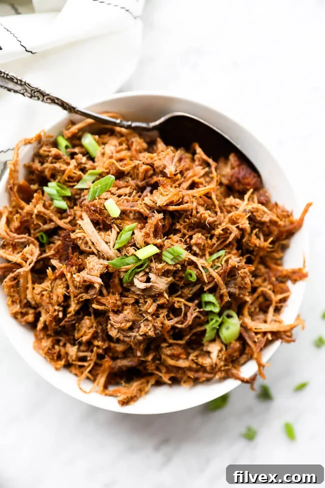 Easy slow cooker pulled pork in a bowl with sliced green onions on top vertical overhead image