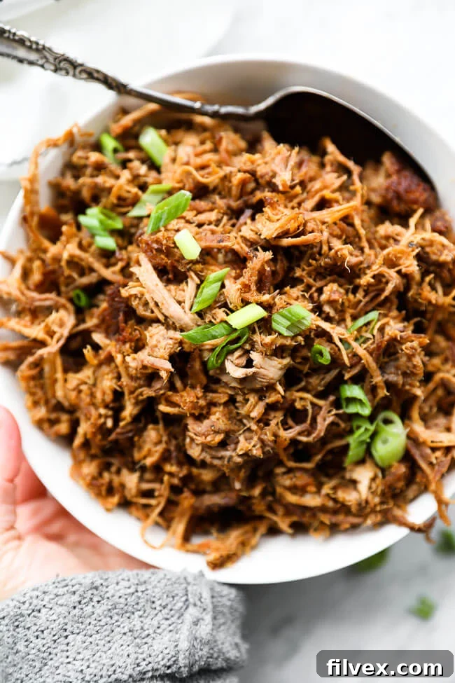 bowl of shredded slow cooker pulled pork with chopped green onions on top
