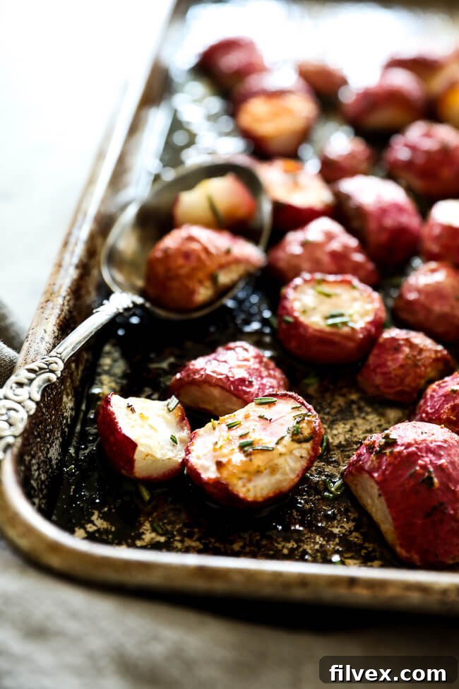 Roasted radishes on sheet pan with spoon close up at an angle vertical image