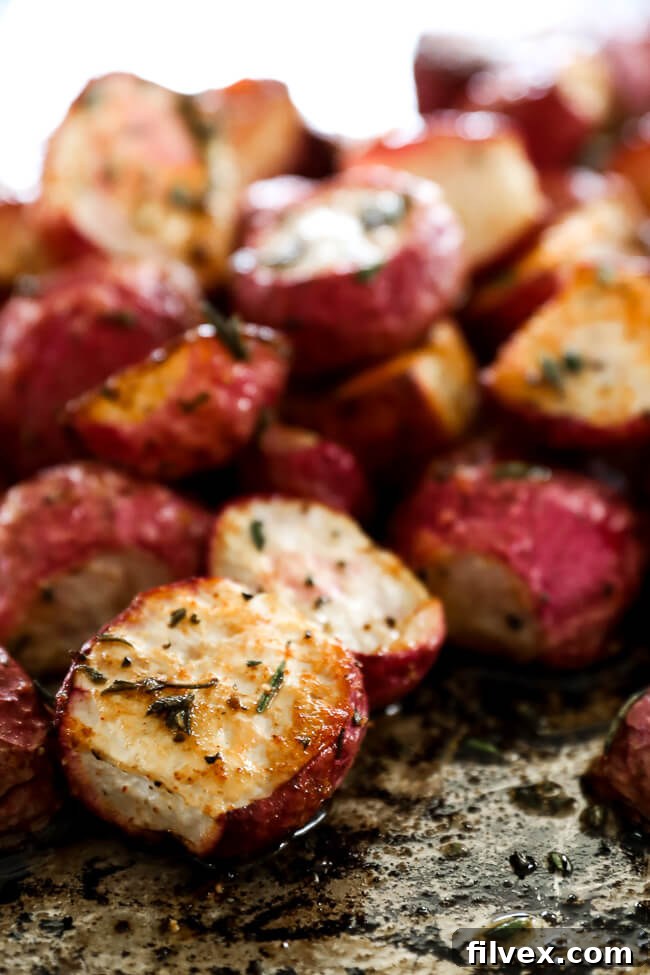 Roasted radishes piled up on sheet pan close up at an angle vertical image