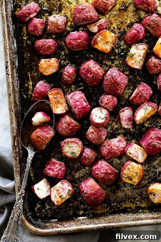 Roasted radishes on sheet pan with spoon overhead vertical image