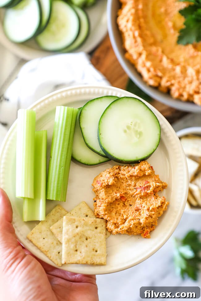 Close-up vertical shot of easy cauliflower hummus on a plate, surrounded by an assortment of fresh, colorful vegetables ready for dipping.