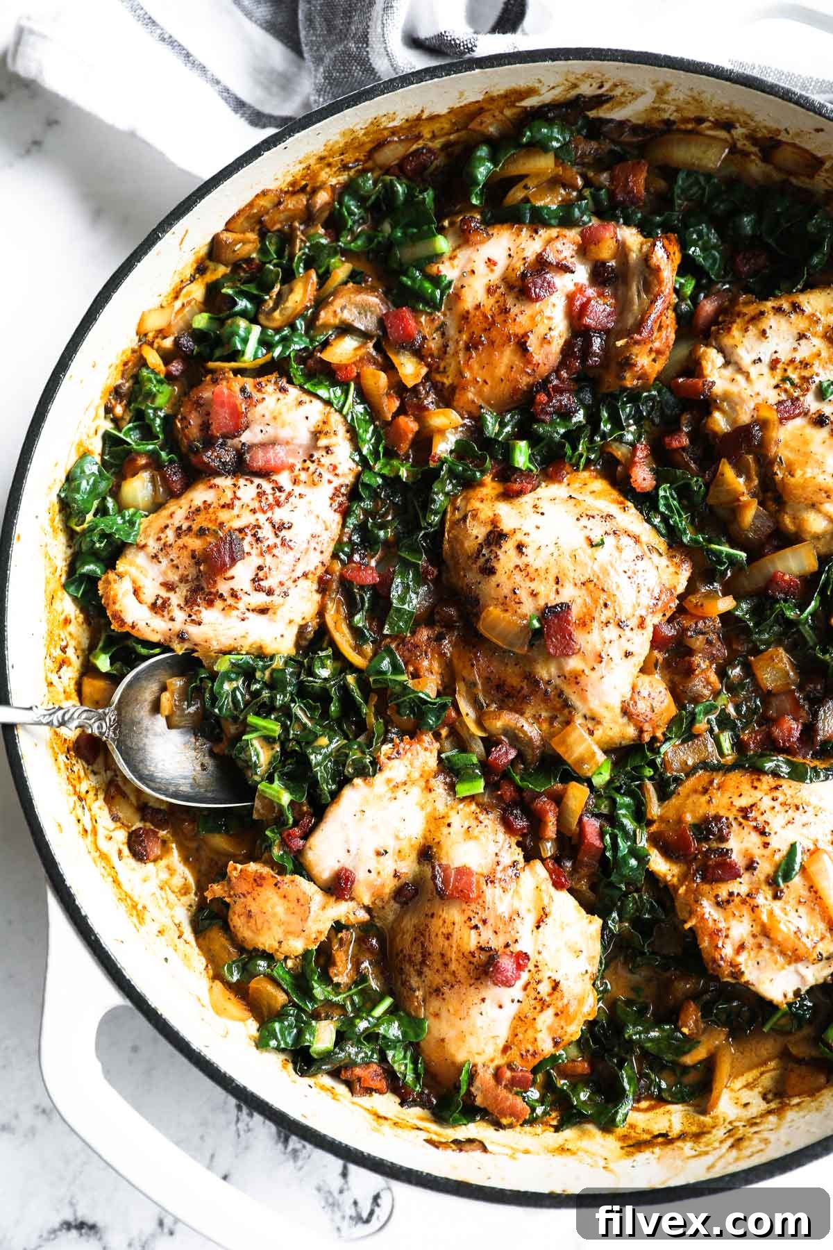 Close-up of creamy mustard chicken in a skillet, garnished with fresh herbs.