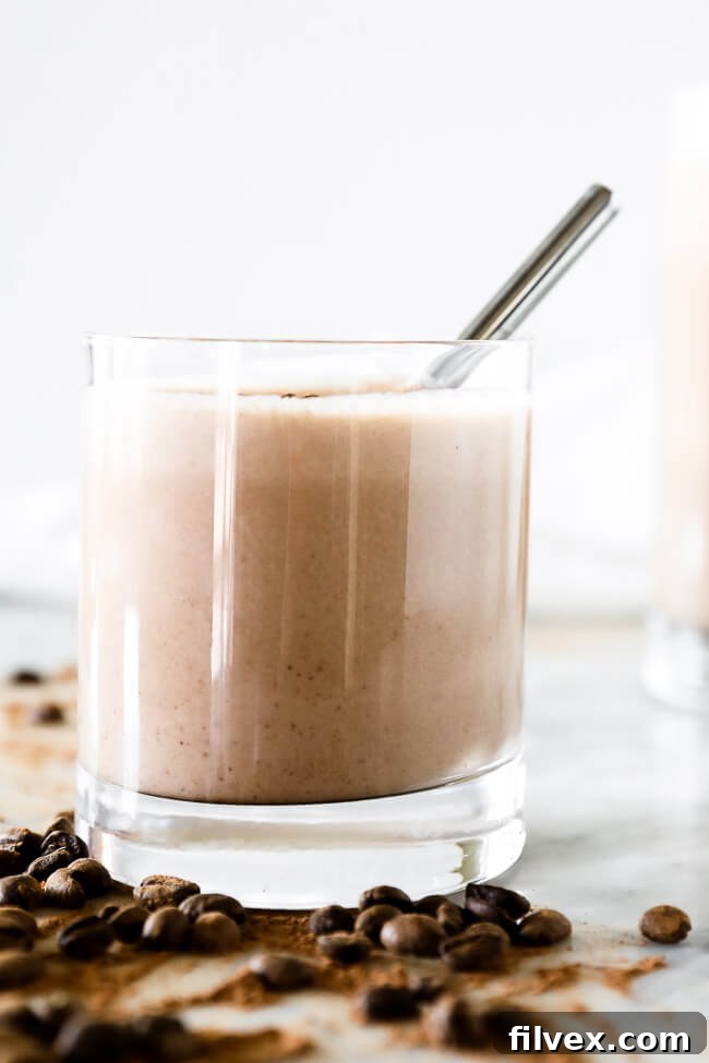 Vertical straight on image of coffee smoothie in a glass a stainless steel straw. 