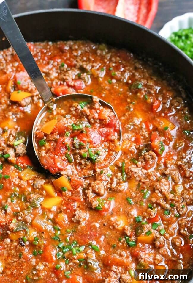 Stuffed pepper soup in a pot with a ladle scooping some out, shown at an inviting angle.
