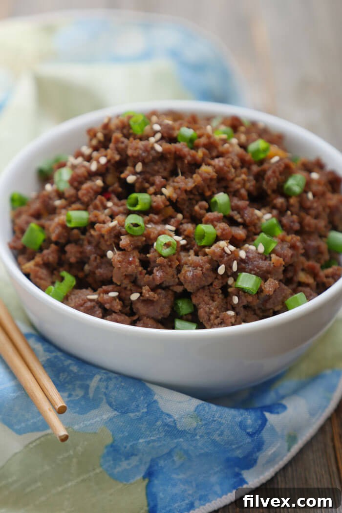 Bowl of Korean beef bulgogi with sliced green onion and sesame seeds as garnish.