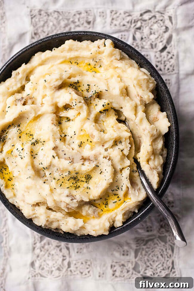 Instant Pot mashed potatoes in a bowl with a spoon and butter on top, photographed from overhead.
