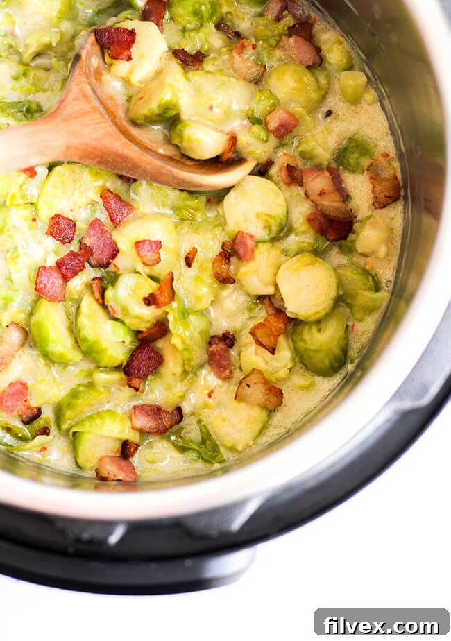 Creamy Brussels sprouts with bacon and a wooden spoon in the Instant Pot, ready to be served.