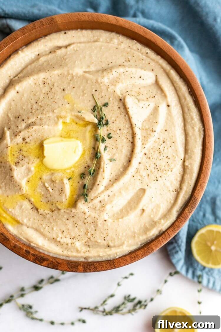 Instant Pot creamy cauliflower mash in a bowl with butter and thyme, viewed from overhead.