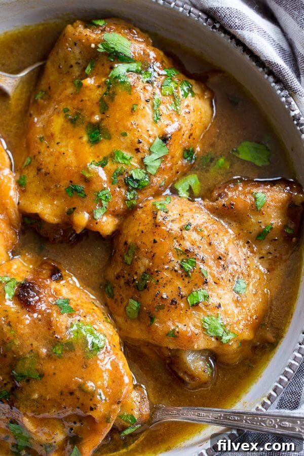 Close up of honey mustard chicken in dish with sauce and spoons, ready to serve.
