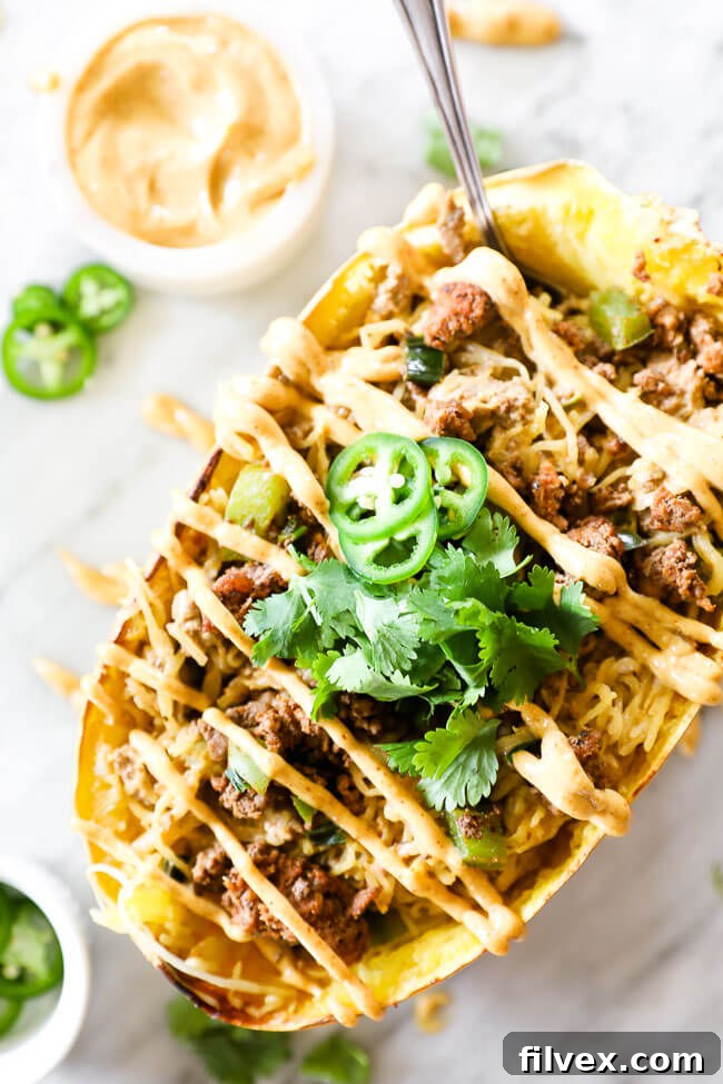 Close-up image of a single taco stuffed spaghetti squash with creamy sauce drizzled on top, showcasing the texture.