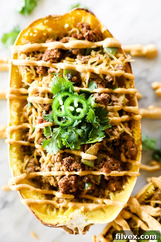 Vertical close-up image of taco stuffed spaghetti squash with sauce, emphasizing its deliciousness.