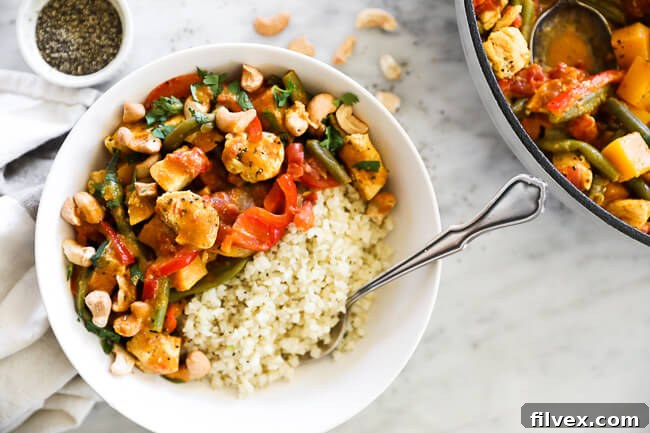 Horizontal overhead image of butternut squash curry served in a bowl with cauliflower rice and fork. 