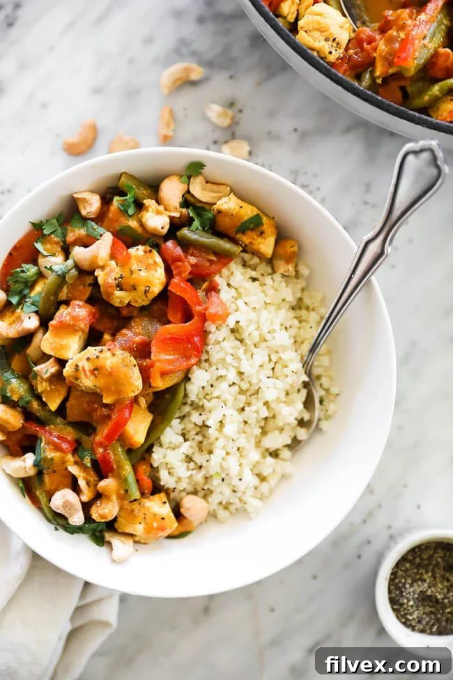 Vertical overhead image of butternut squash curry served in a bowl with cauliflower rice and a fork. 