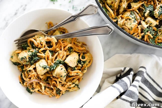 Creamy chicken sweet potato noodles in a bowl with fork and spoon, a vibrant and healthy family dinner
