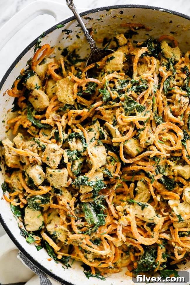 Overhead shot of creamy chicken sweet potato noodles in a pan, beautifully garnished with fresh herbs and ready to serve