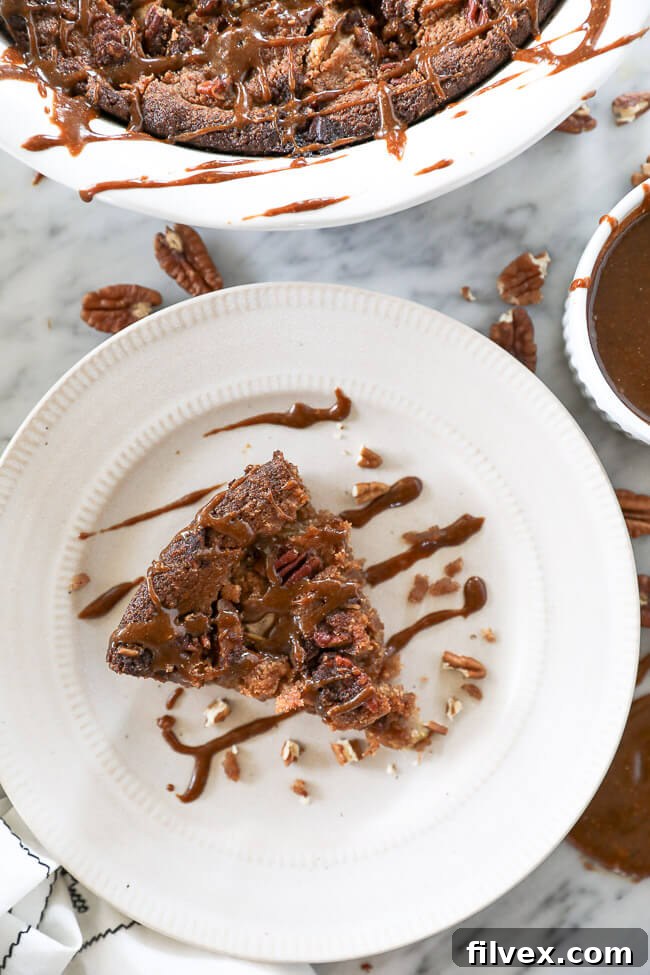Piece of gluten-free apple cake served on a plate with caramel sauce drizzled on top. 