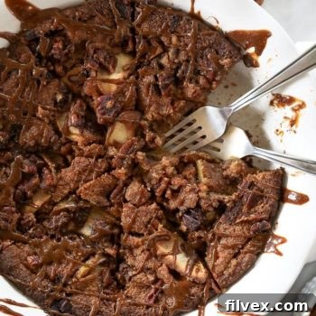Gluten-free apple cake in a pie dish with piece removed and two forks dug in. Caramel sauce drizzled all over top.